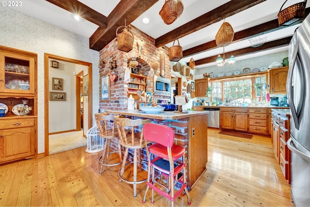 kitchen with a chandelier, decorative light fixtures, stainless steel appliances, light hardwood / wood-style floors, and beamed ceiling