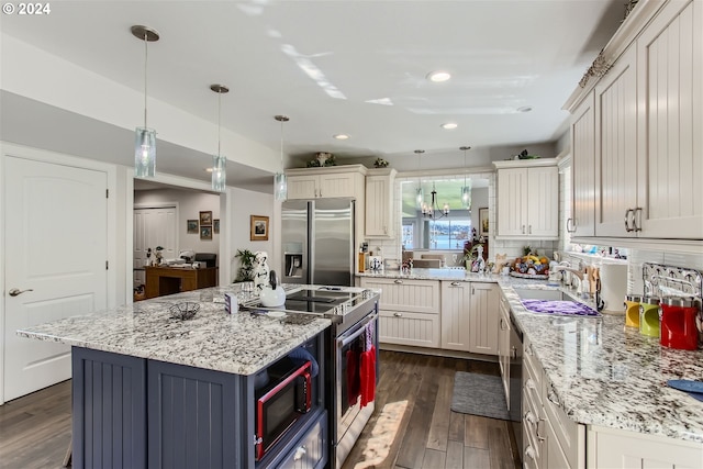 kitchen with stainless steel appliances, decorative light fixtures, decorative backsplash, a kitchen island, and dark hardwood / wood-style flooring