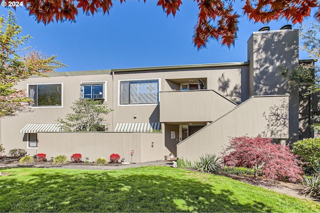 view of front of property featuring a front yard and a balcony