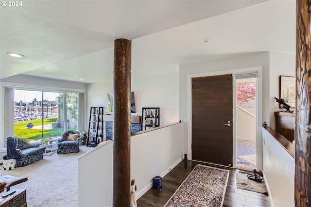 foyer entrance with a textured ceiling and dark colored carpet