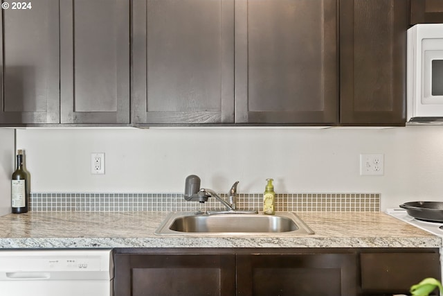 kitchen featuring dishwashing machine, sink, and dark brown cabinets