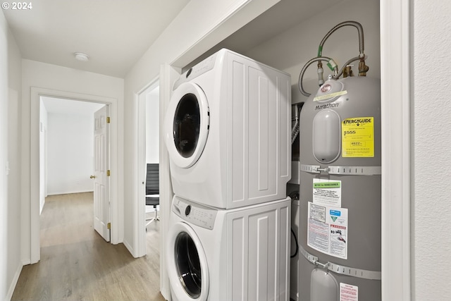 laundry area with light wood-type flooring, stacked washer / dryer, and water heater