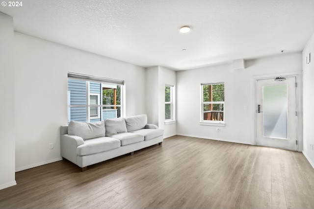 unfurnished living room featuring a textured ceiling, hardwood / wood-style flooring, and plenty of natural light