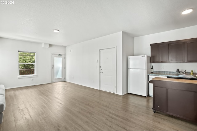 kitchen featuring sink, a textured ceiling, dark brown cabinets, white fridge, and dark hardwood / wood-style flooring