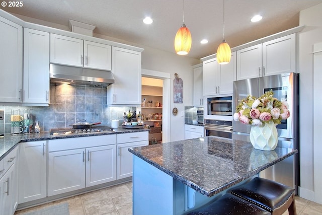 kitchen with white cabinets, appliances with stainless steel finishes, and a breakfast bar area