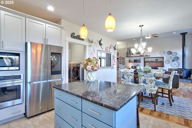 kitchen featuring a wood stove, white cabinetry, hanging light fixtures, and appliances with stainless steel finishes