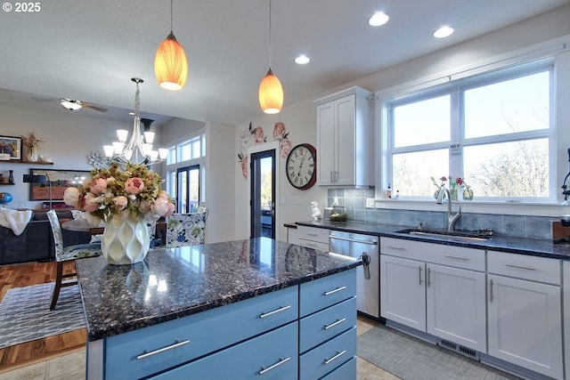 kitchen with stainless steel dishwasher, white cabinets, a kitchen island, sink, and pendant lighting