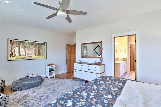 bedroom featuring ceiling fan, connected bathroom, a textured ceiling, and light wood-type flooring