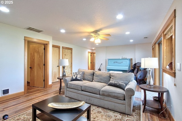 living room featuring hardwood / wood-style floors, a textured ceiling, and ceiling fan