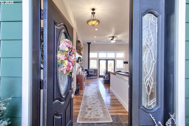 entryway with a wood stove, ceiling fan, and dark hardwood / wood-style flooring