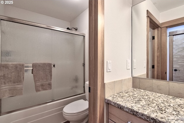 full bathroom featuring bath / shower combo with glass door, toilet, vanity, and tasteful backsplash