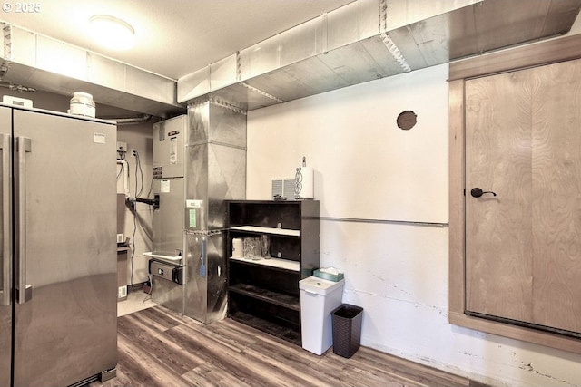 basement with hardwood / wood-style flooring and stainless steel fridge