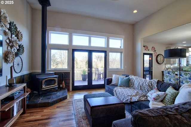 living room with wood-type flooring, a wood stove, and french doors