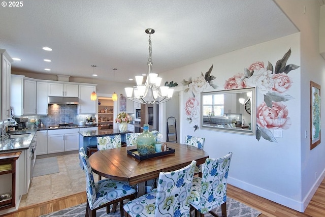 dining space featuring sink, light hardwood / wood-style floors, and a chandelier