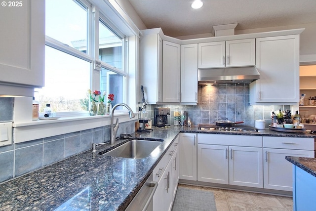 kitchen with stainless steel gas stovetop, sink, white cabinetry, tasteful backsplash, and dark stone countertops