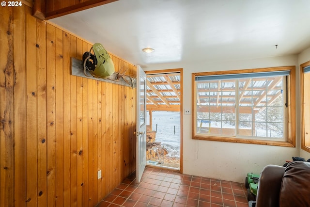 doorway to outside featuring dark tile patterned floors and wood walls