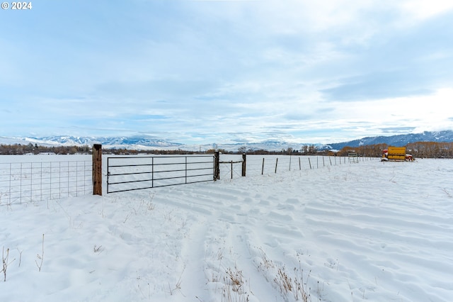 yard covered in snow featuring a mountain view and a rural view