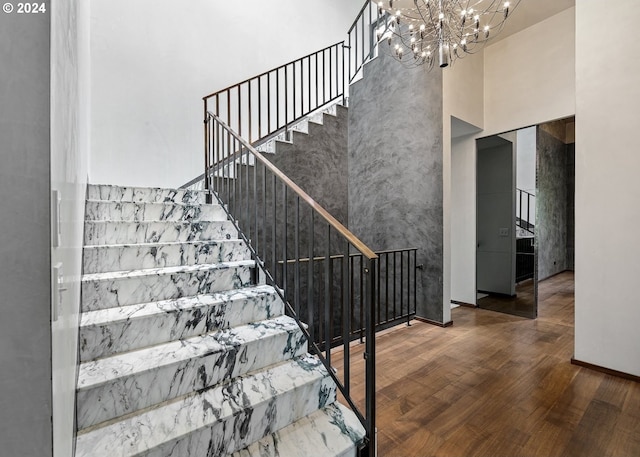 stairs with a notable chandelier, a towering ceiling, and hardwood / wood-style floors