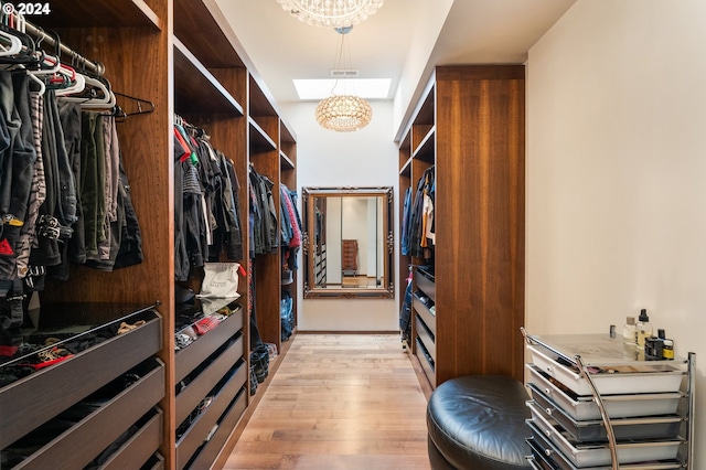 spacious closet with a notable chandelier and light hardwood / wood-style floors