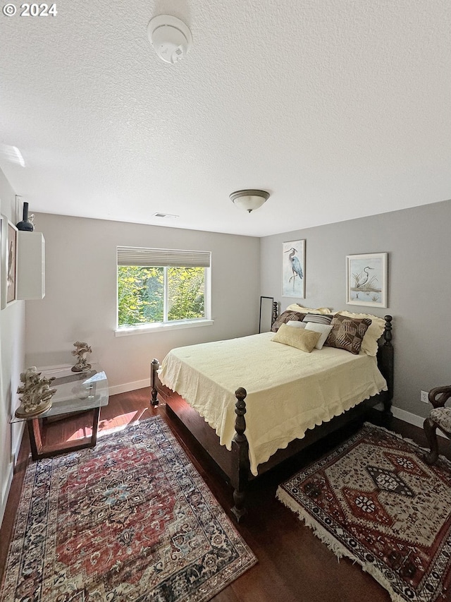 bedroom with a textured ceiling and dark wood-type flooring