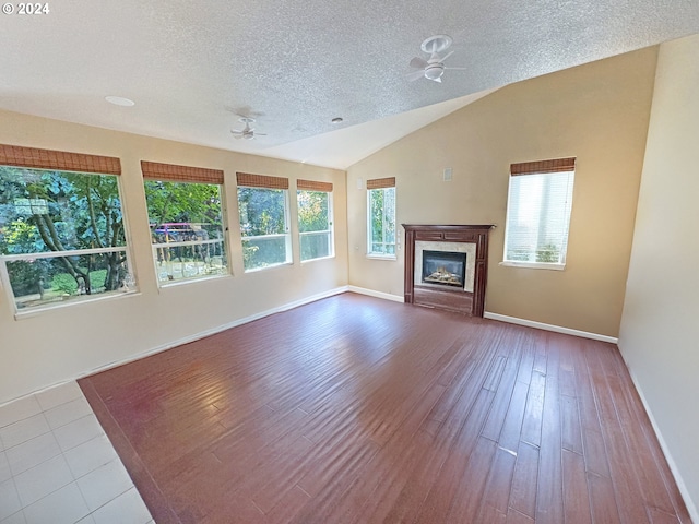 unfurnished living room featuring ceiling fan, a textured ceiling, lofted ceiling, and light hardwood / wood-style floors