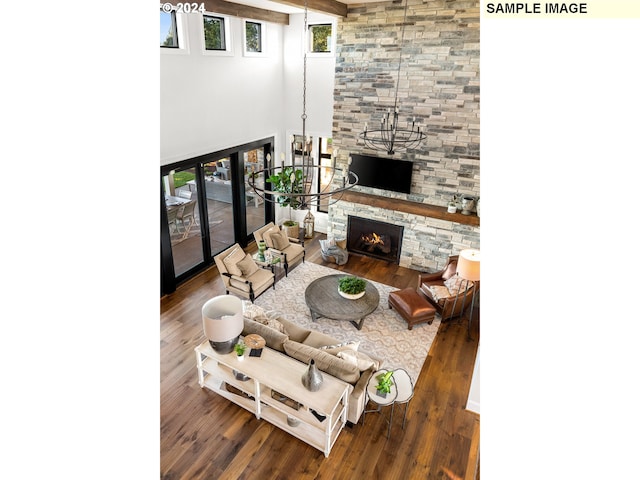 living room featuring a towering ceiling, a fireplace, dark hardwood / wood-style flooring, and a chandelier