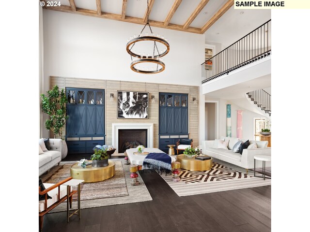 living room featuring dark wood-type flooring, a towering ceiling, beam ceiling, and an inviting chandelier