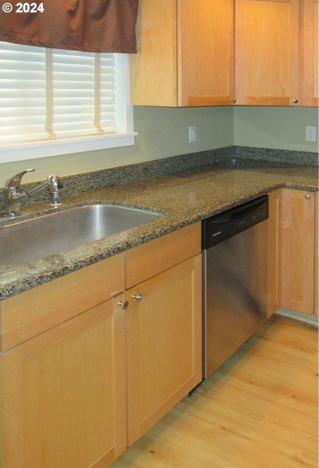 kitchen featuring sink, dark stone counters, dishwasher, and light wood-type flooring