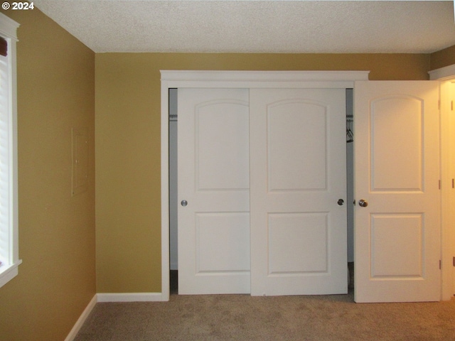 unfurnished bedroom with a closet, light carpet, and a textured ceiling