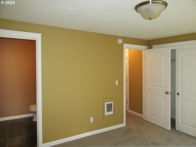 unfurnished bedroom featuring ensuite bath and carpet flooring