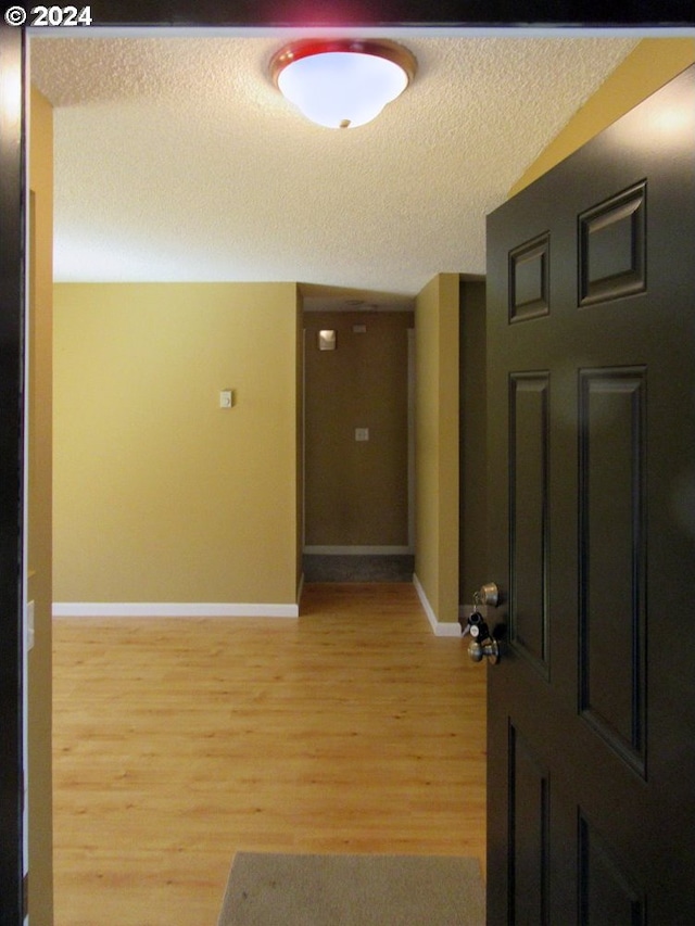 hallway featuring light hardwood / wood-style flooring and a textured ceiling