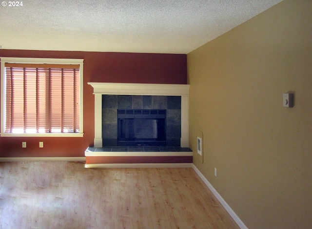 unfurnished living room with hardwood / wood-style floors, a fireplace, and a textured ceiling