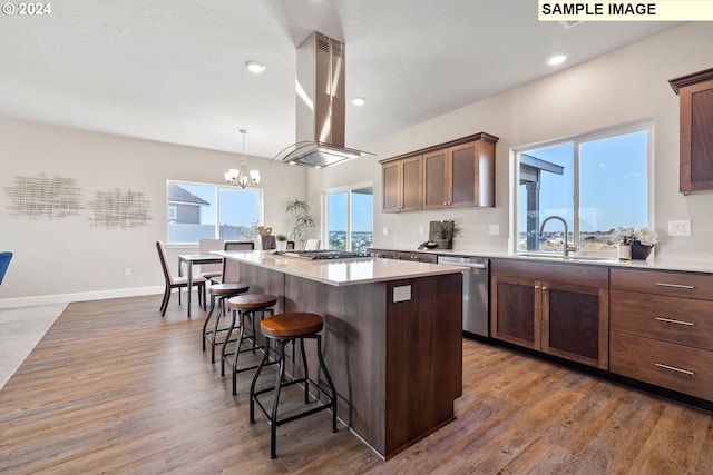 kitchen featuring stainless steel dishwasher, island range hood, a kitchen bar, a center island, and a sink