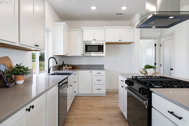 1588 NE 8th Pl, Hermiston, OR 97838 - kitchen with stainless steel appliances, wall chimney range hood, light wood-type flooring, white cabinetry, and recessed lighting