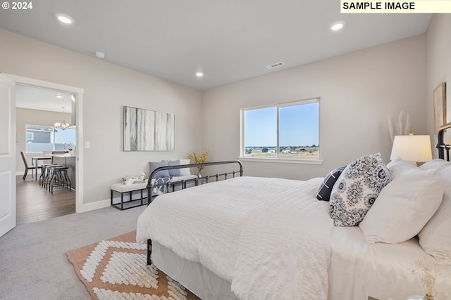 carpeted bedroom with an inviting chandelier, baseboards, recessed lighting, and visible vents