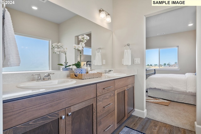 bathroom with double vanity, a sink, connected bathroom, and wood finished floors