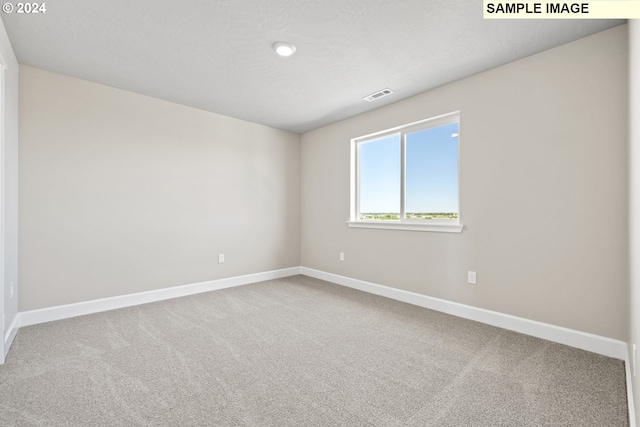 carpeted empty room featuring baseboards and visible vents