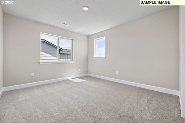 spare room featuring baseboards, visible vents, and carpet