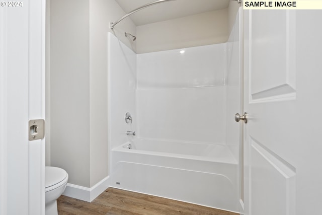 bathroom with baseboards, toilet, wood finished floors, and tub / shower combination