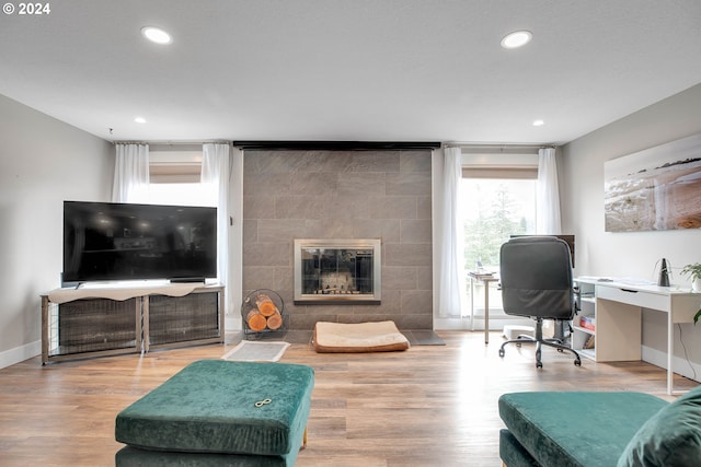 home office with a tiled fireplace and hardwood / wood-style floors