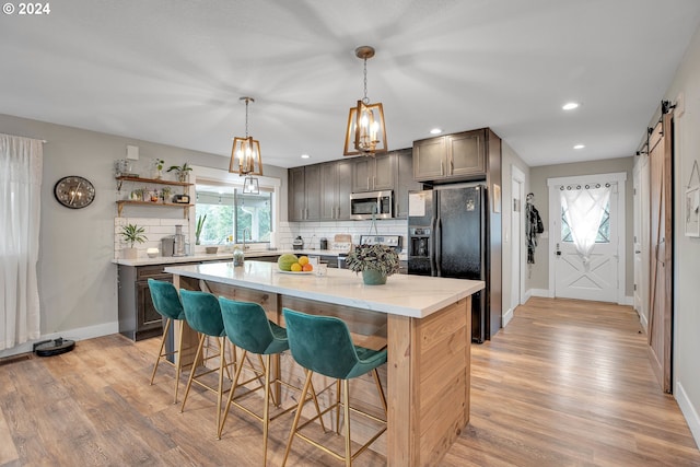 kitchen featuring appliances with stainless steel finishes, a barn door, a kitchen island, and light hardwood / wood-style floors