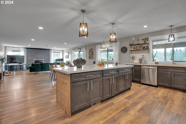 kitchen featuring stainless steel dishwasher, hanging light fixtures, plenty of natural light, and a large fireplace