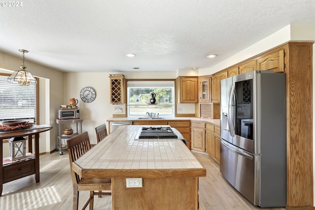 kitchen featuring a center island, sink, hanging light fixtures, light hardwood / wood-style flooring, and appliances with stainless steel finishes