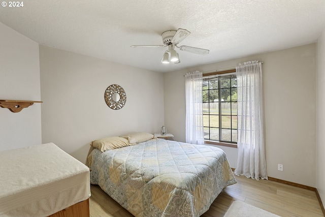 bedroom featuring ceiling fan, a textured ceiling, and light wood-type flooring