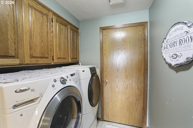 washroom with washer and clothes dryer, cabinets, and a textured ceiling