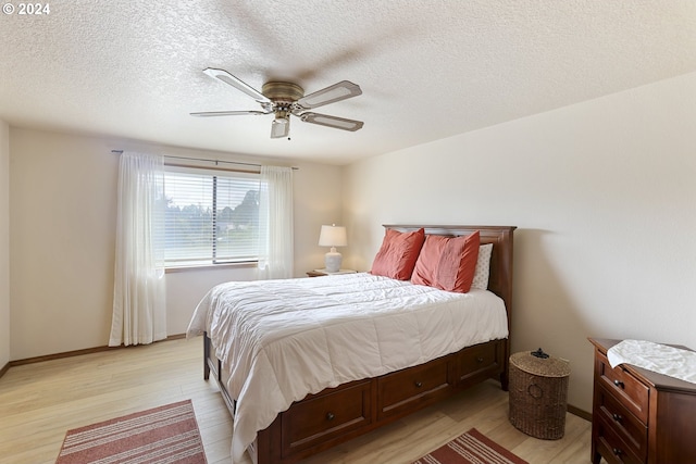 bedroom featuring light hardwood / wood-style floors, ceiling fan, and a textured ceiling