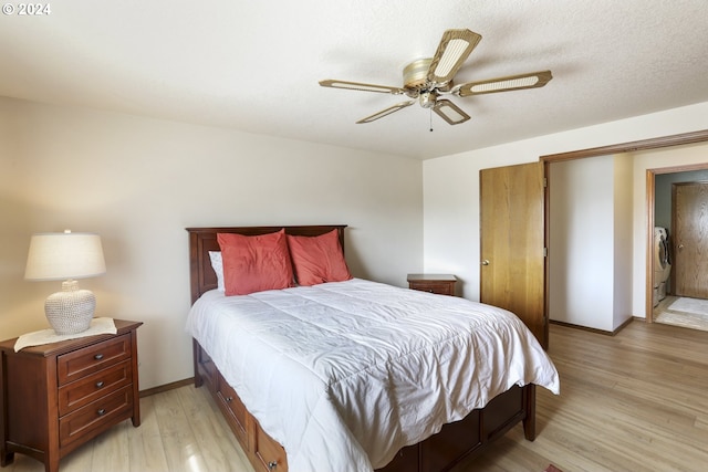 bedroom with light wood-type flooring, a textured ceiling, separate washer and dryer, and ceiling fan