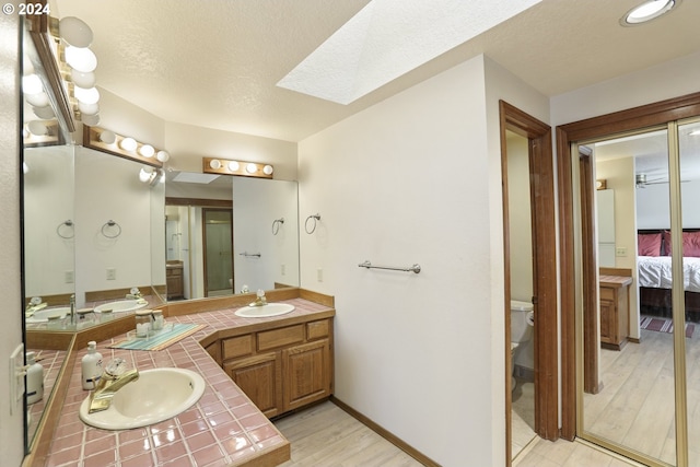 bathroom with vanity, a skylight, hardwood / wood-style floors, and a textured ceiling