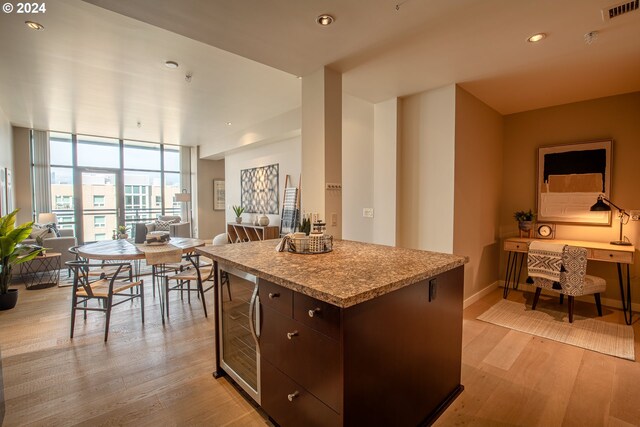 1025 NW Couch St Unit 1020, Portland, OR 97209 - kitchen featuring wine cooler, light wood-style floors, dark brown cabinetry, a kitchen island, and open floor plan