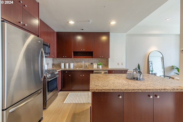 kitchen featuring decorative backsplash, light wood-type flooring, sink, and appliances with stainless steel finishes